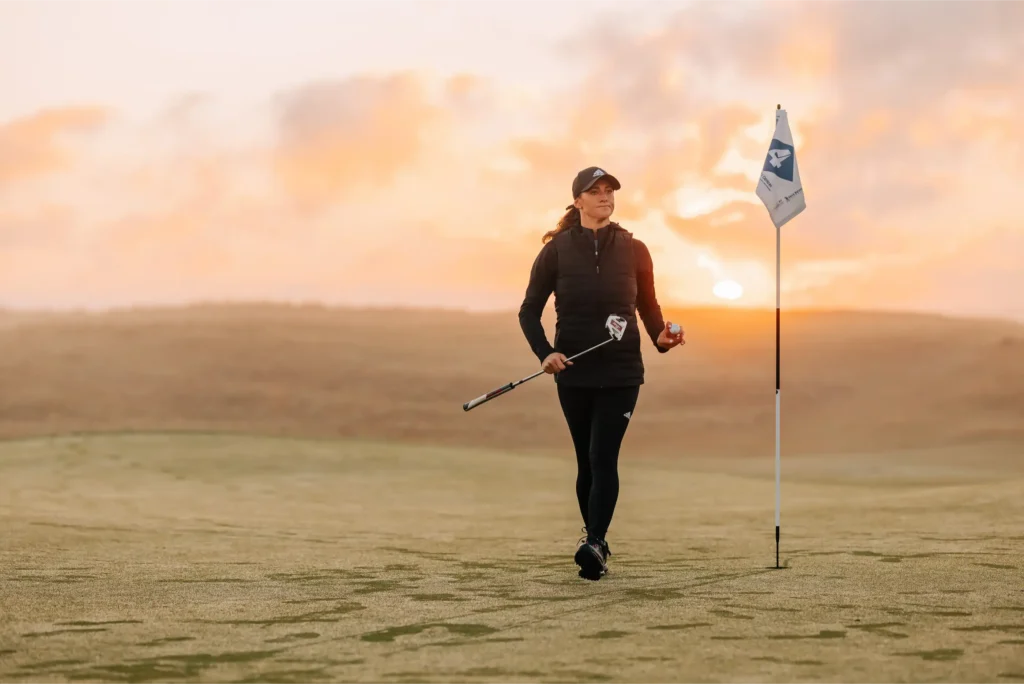Lady golfer on a scenic coastal course at sunset, participating in a ladies golf competitions in Cornwall