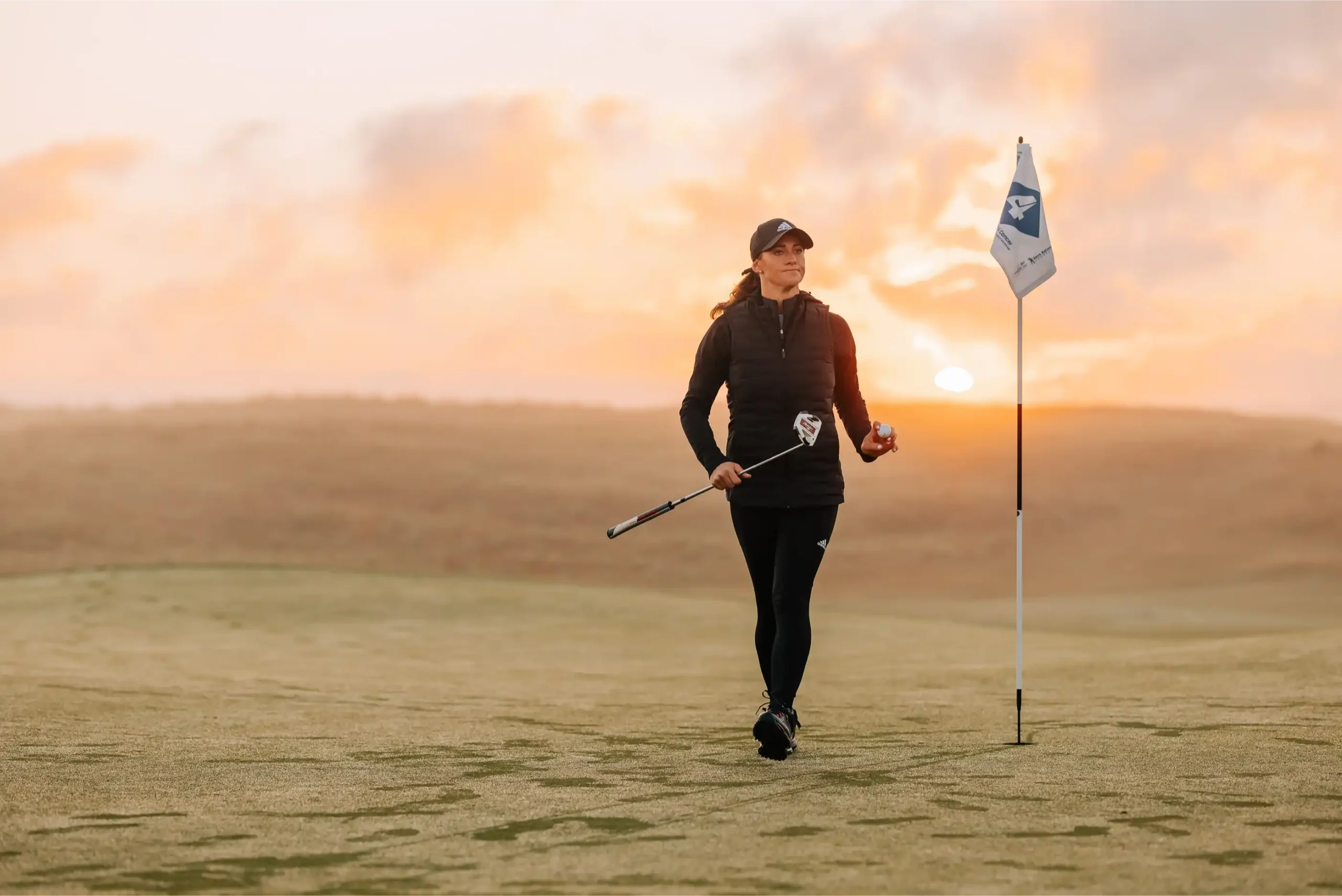 Lady golfer on a scenic coastal course at sunset, participating in a ladies golf competitions in Cornwall